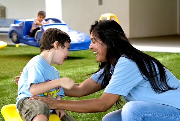 teacher in blue shirt helping student on playground