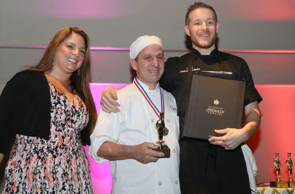 arc culinary student accepting award with two others
