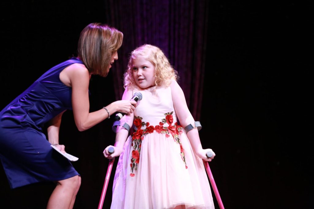 woman on stage holding microphone for young girl