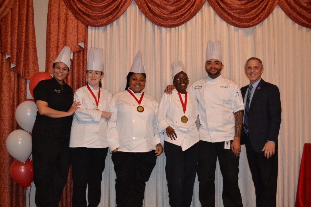 arc culinary students pose for photo in chef coats with medals around their necks