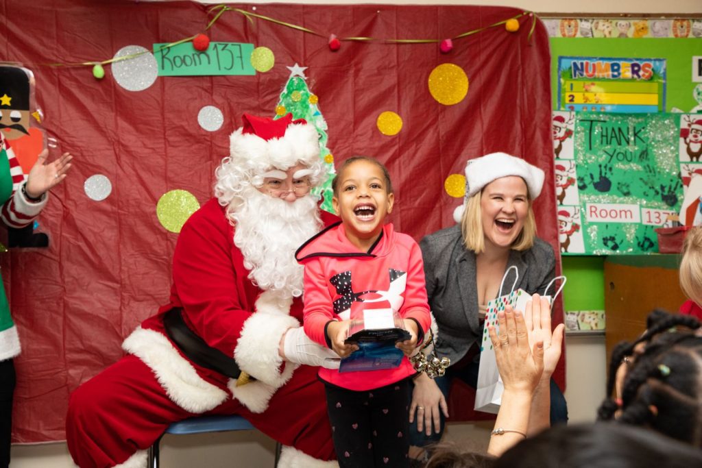a child smiles excitedly in front of santa claus