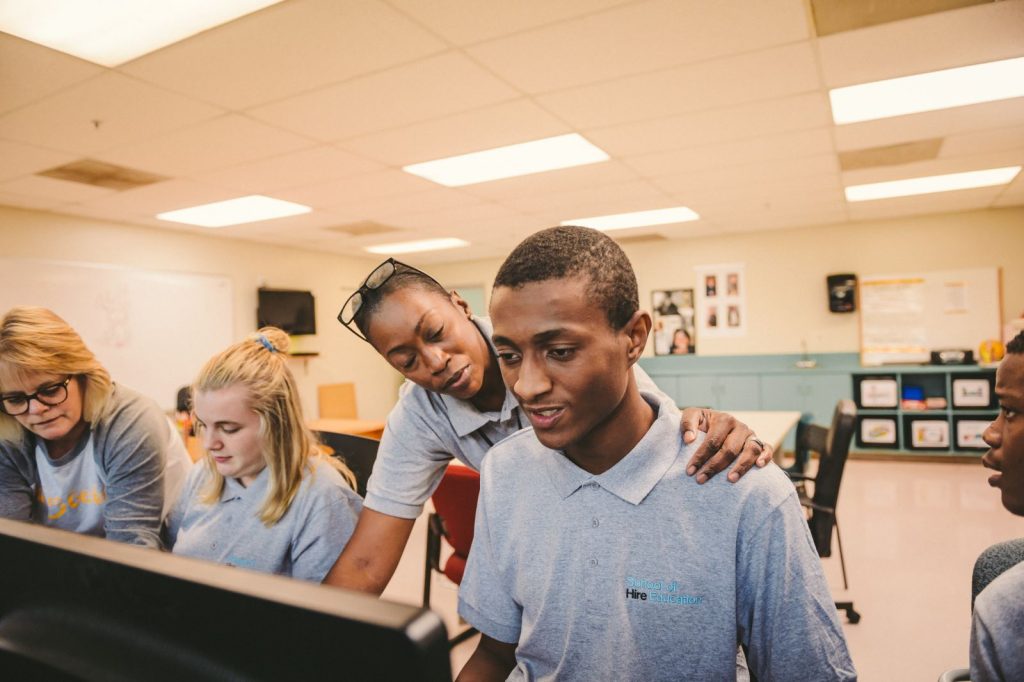 instructor helping young adult student on a computer