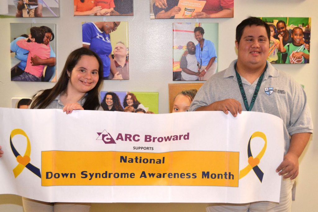 two adults with down syndrome holding down syndrome awareness month banner