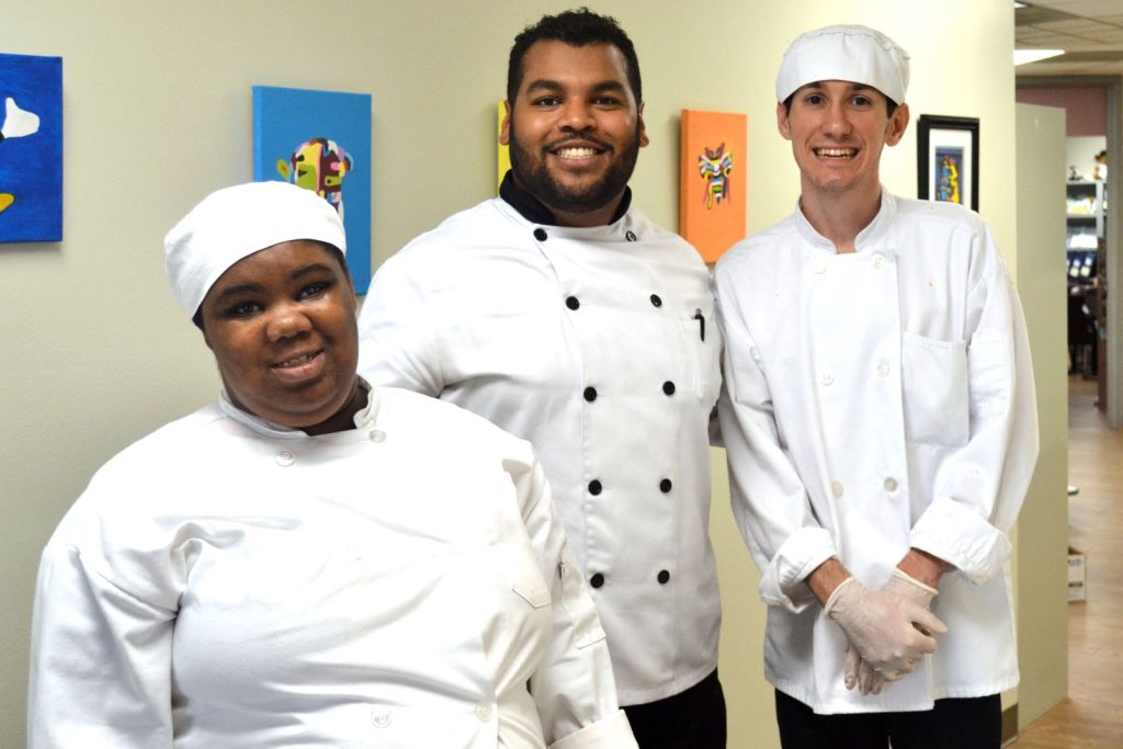 three adults in chef uniforms posing for a photo