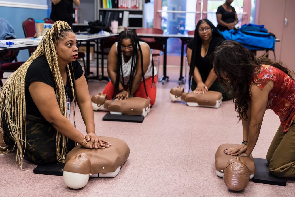 adults performing cpr on triaining dummies
