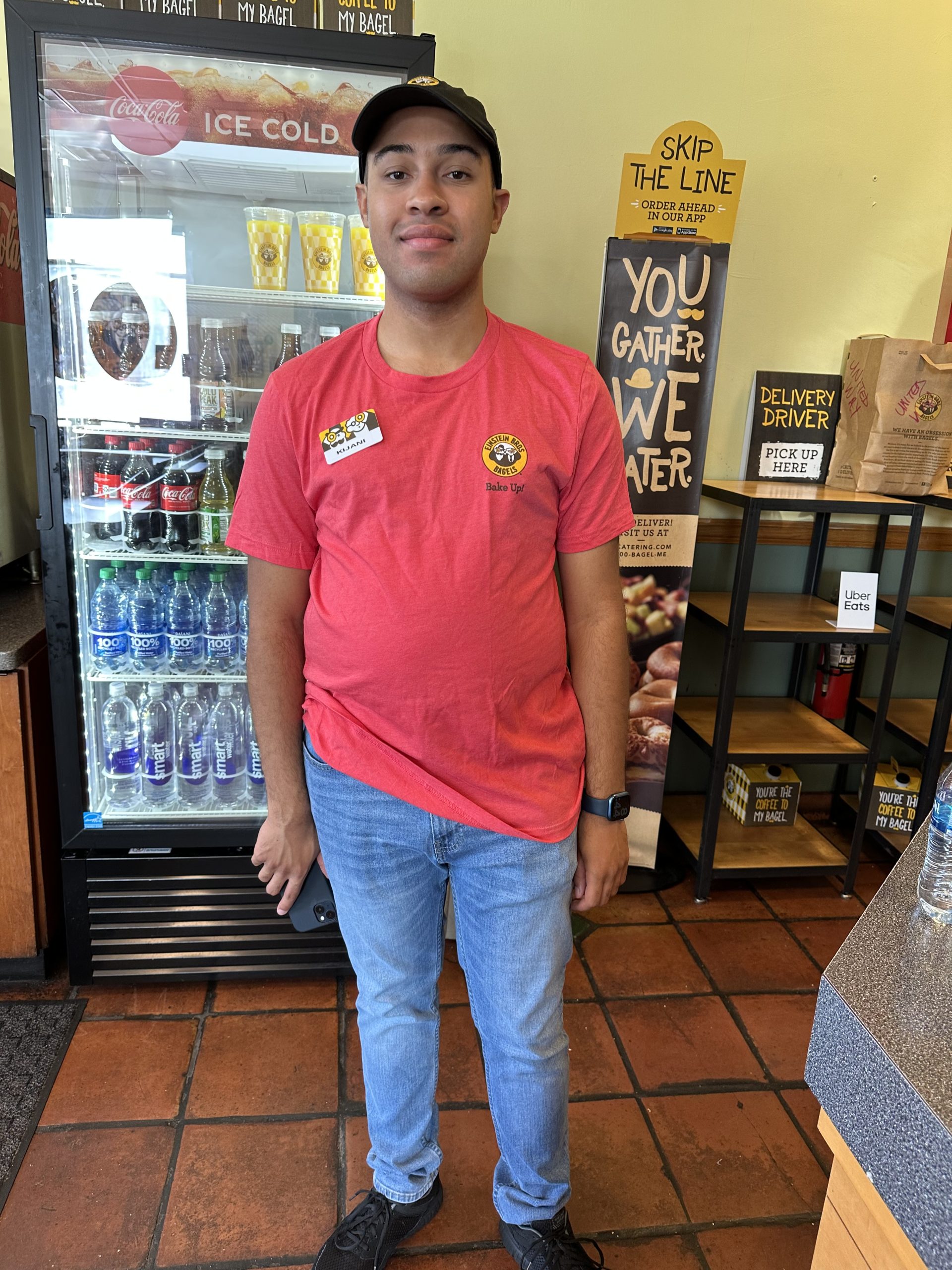 young man standing in a restaurant with his red uniform shirt on 
