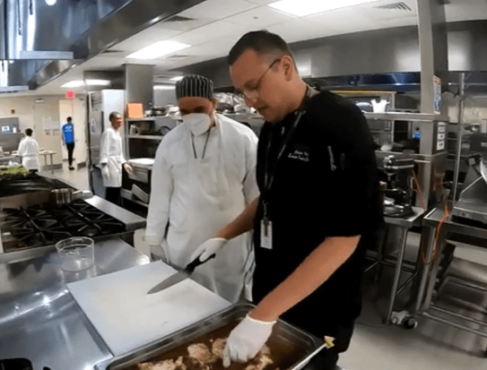 chef in black uniform shows student knife skills